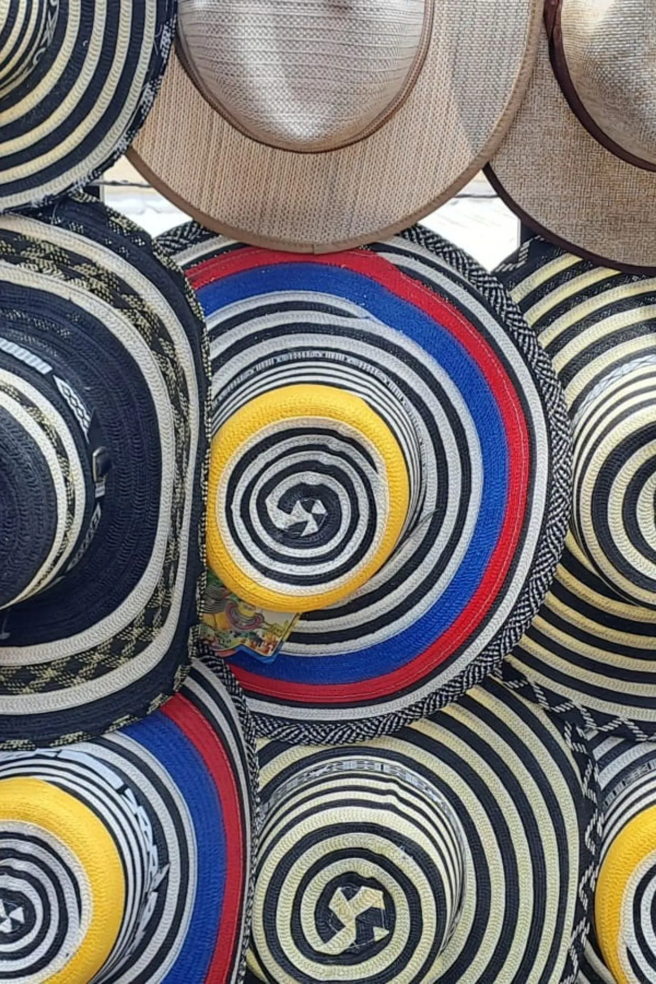 Close-up van een verzameling traditionele Colombiaanse hoeden, waaronder zwart-wit gestreepte sombrero vueltiao en hoeden met kleurrijke ringen in geel, blauw en rood.